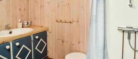 Une salle de bain avec un mur en bois, un lavabo, un miroir, une douche et des toilettes.