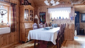 Ein Esszimmer mit Holzboden, einem Tisch für vier Personen, einer Vitrine mit Glastüren und einem Fenster mit Karottenvorhängen.