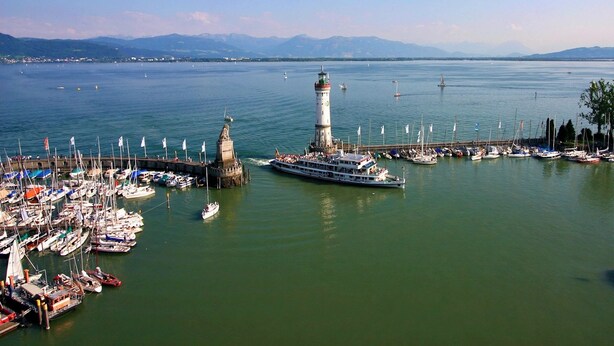Un puerto deportivo con barcos, un faro destacado y un gran crucero amarrado.