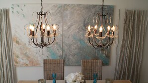 Un comedor con dos candelabros, sillas de mimbre y una mesa dispuesta con manteles individuales y adornos.