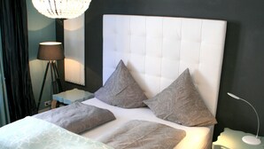 Una cama bien hecha con un cabecero capitonado, dos almohadas y una colcha estampada.