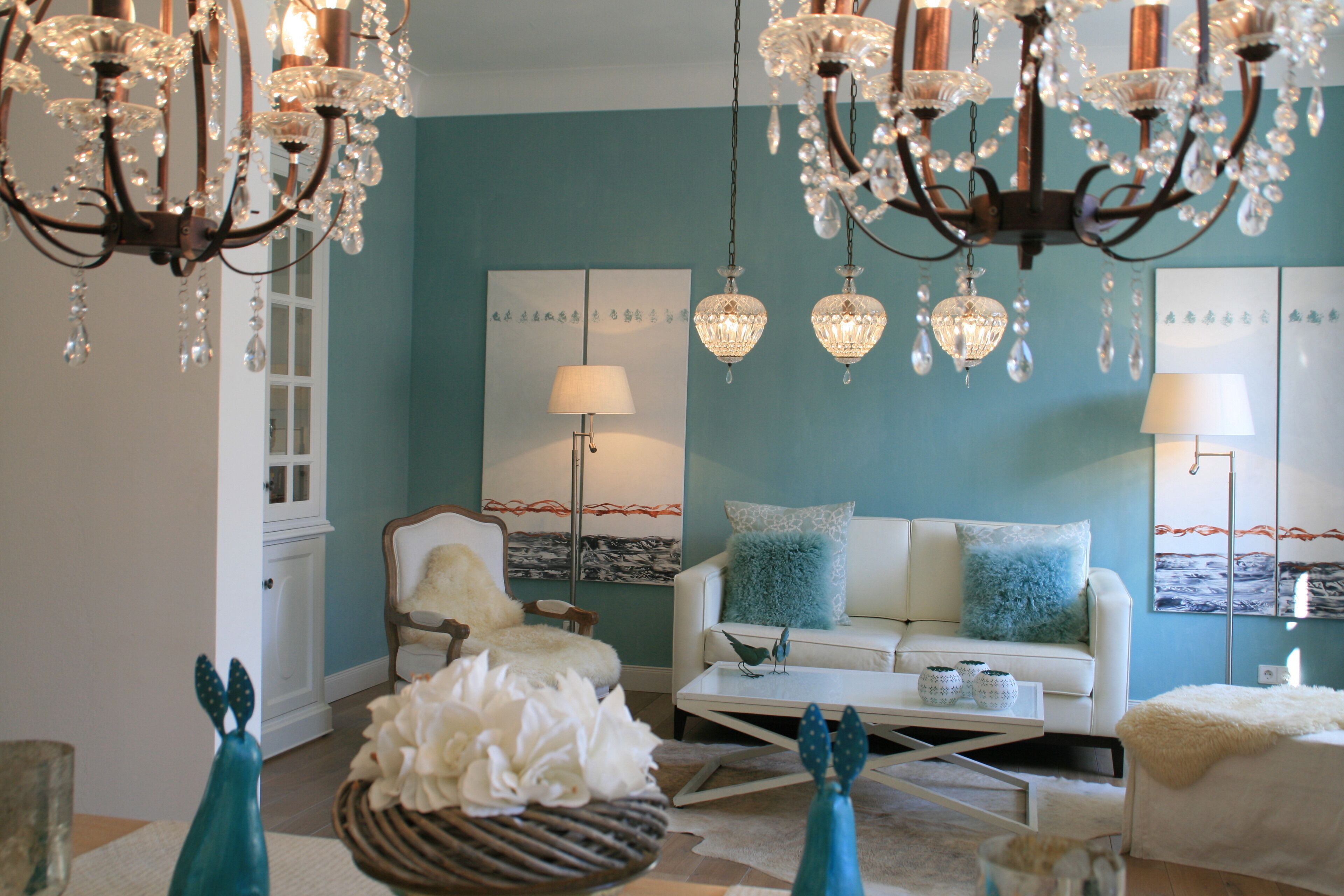 Un salon avec un mur de couleur turquoise, un canapé blanc et un lustre.