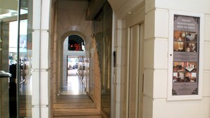 Un pasillo con una puerta de vidrio a la izquierda y un cartel anunciando habitaciones de hotel a la derecha.