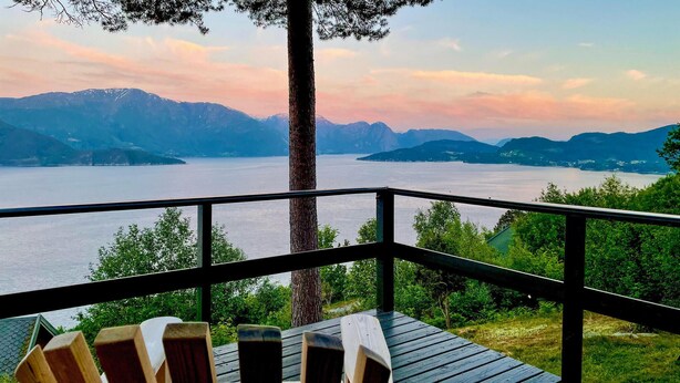 A wooden deck with Adirondack chairs overlooking a lake and mountains. - Lovely home in Norheimsund with WiFi (Norheimsund)
