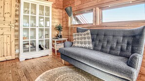 A cozy cabin interior with a grey sofa, a white cabinet with glass doors, and a round patterned rug. - Lovely home in Norheimsund with WiFi (Norheimsund)