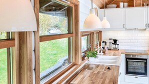 A modern kitchen with large windows, wooden flooring, white cabinets, and stainless steel appliances. - Lovely home in Norheimsund with WiFi (Norheimsund)