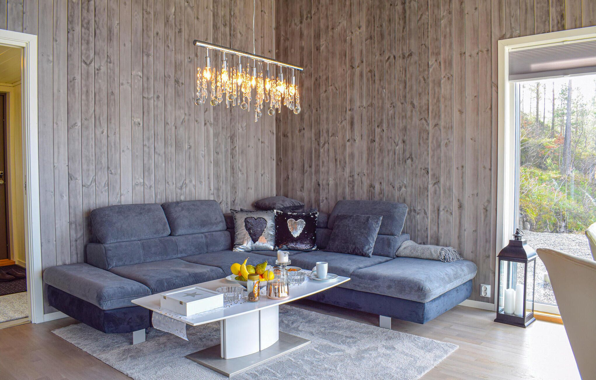 A modern living room with a grey sectional sofa, a white coffee table, and a chandelier.