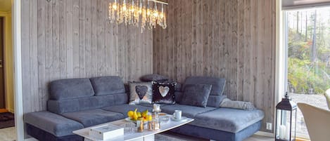 Een moderne woonkamer met een grijze modulaire bank, een witte salontafel en een kroonluchter.