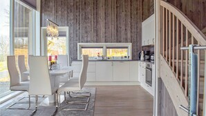 Une cuisine moderne avec des meubles blancs, un îlot central et un coin repas avec des chaises blanches.