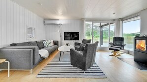 A modern living room with a sofa, armchairs, a TV, and a fireplace.