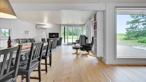A modern living room with a sofa, dining table, and chairs, a TV, and a bookshelf.