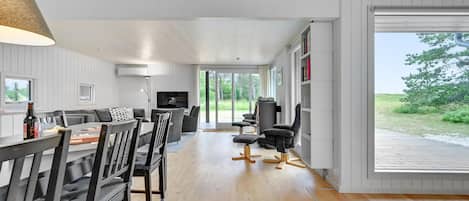 Una sala de estar moderna con sofá, mesa de comedor, sillas, televisor y estantería.