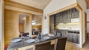 A modern kitchen with dark wood cabinets, a built-in oven, and a microwave.