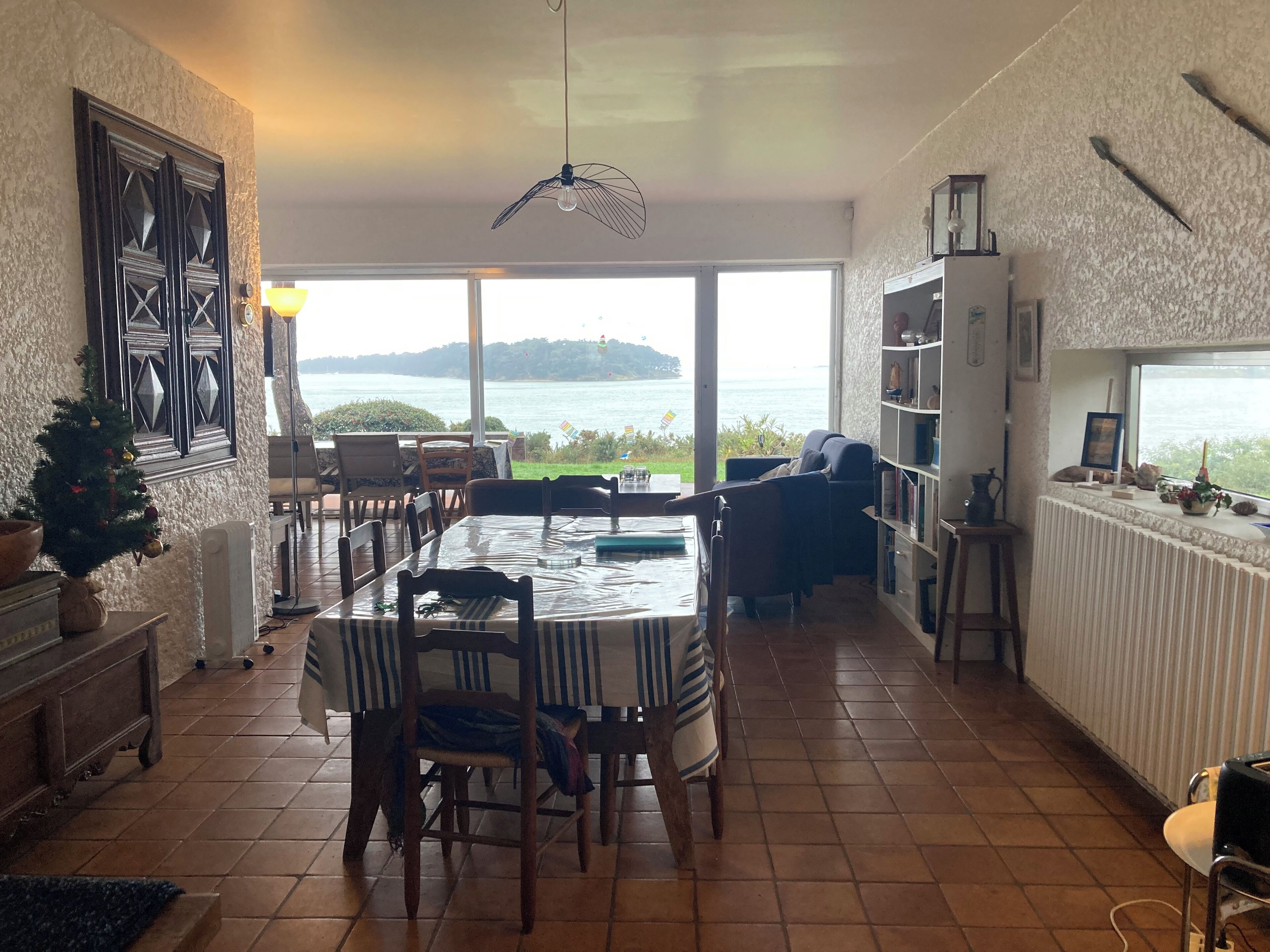 Un coin repas avec une table et des chaises, une bibliothèque et une vue sur la mer.