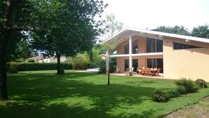 Una casa moderna de dos plantas con un patio que tiene una mesa y sillas.