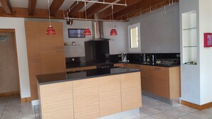 Una cocina moderna con armarios de madera, encimera negra y lámparas colgantes rojas.