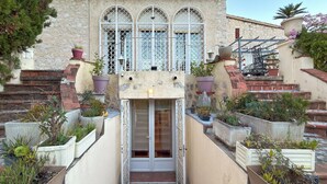 A stone building with a central entrance, flanked by potted plants and a metal gate.