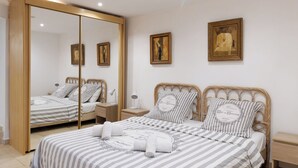 A bedroom with a large mirror, two beds with striped bedding, and two bedside tables.
