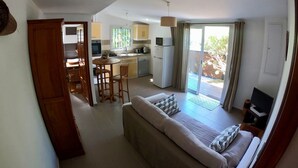 A compact living space with a kitchenette, a dining area, and a sofa with a TV. - Le Veloutier: Between sea, mountain and volcano (l'Étang-Salé les Bains)