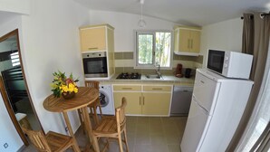 A compact kitchen with a dining area, including a table with chairs, a washing machine, a microwave, and a refrigerator. - Le Veloutier: Between sea, mountain and volcano (l'Étang-Salé les Bains)
