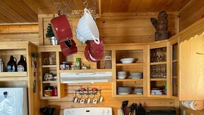 A kitchen with wooden cabinets, a stove, and hanging pots. - YEAR-ROUND Private, Cozy Lakeside Cabin. Beautiful Views, 2 Boats, Kayak & Canoe (Ironton)
