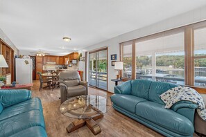 A spacious living area with a blue sofa, a glass coffee table, and a dining area with wooden cabinets.