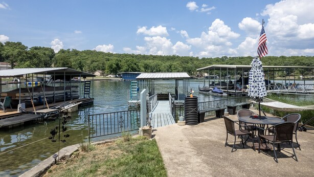 A lakeside dock with boats, a covered seating area, and an American flag.