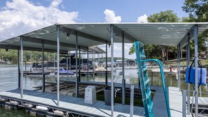 A covered dock with a metal railing, a lifeguard stand, and a boat in the background.