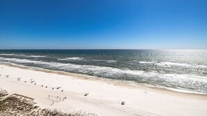 Una spiaggia con cielo sereno, onde e una battigia sabbiosa.