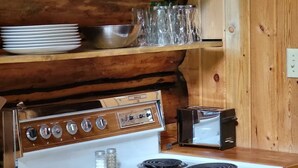 Cozinha com fogão branco, prateleiras de madeira e um relógio de parede rústico.