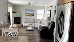 A spacious living area with a fireplace, a sofa, a dining table, and a kitchen with a refrigerator.