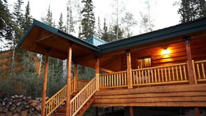 A wooden cabin with a covered porch and a staircase leading to a deck.