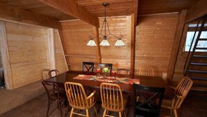A wooden dining room with a large table, chairs, and a chandelier.