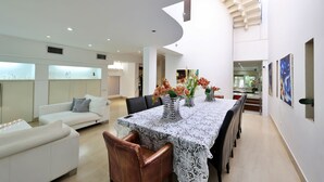 A spacious dining area with a high ceiling and a central table adorned with a lace tablecloth.