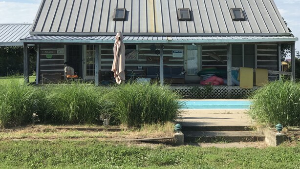 Une cabane en rondins avec un toit en métal, une véranda et une piscine.