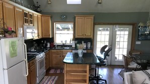 Une cuisine avec des meubles de rangement en bois, un réfrigérateur, une cuisinière, un évier et un coin repas comprenant une table et des chaises.