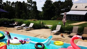 Une piscine avec différents jeux gonflables et des chaises longues.