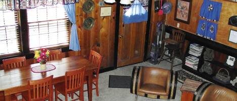 A dining area with a wooden table and chairs, a vase of flowers, and a window with blinds.