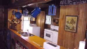 A kitchen with wooden walls, a white stove, a sink, and a toaster. - Pine Crest- Historic 3 bedroom Log Cabin built in the 1930's by the CCC.   (Custer)
