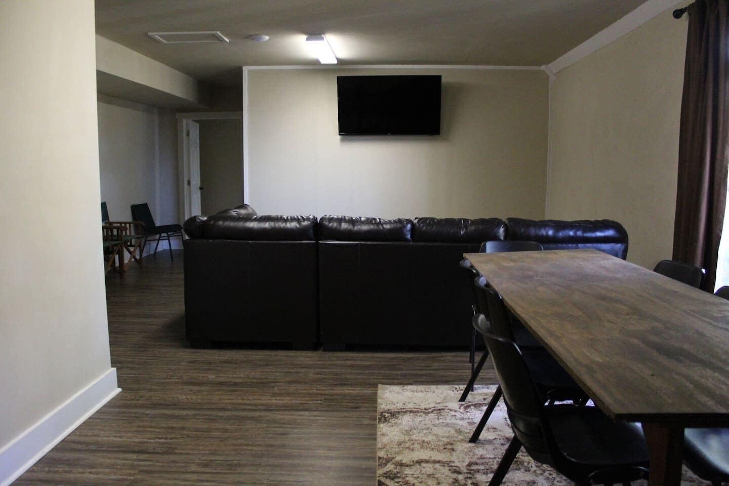 A living room with a sectional sofa, a dining table, and chairs.