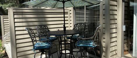 Un patio con una mesa, cuatro sillas, una sombrilla y una terraza de madera.