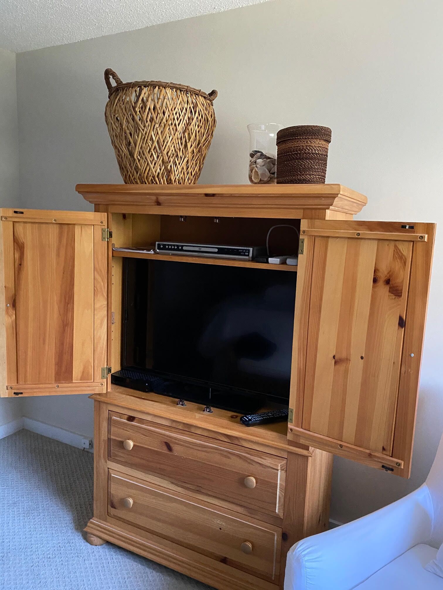 Un mueble de madera con televisor, reproductor de DVD y control remoto.