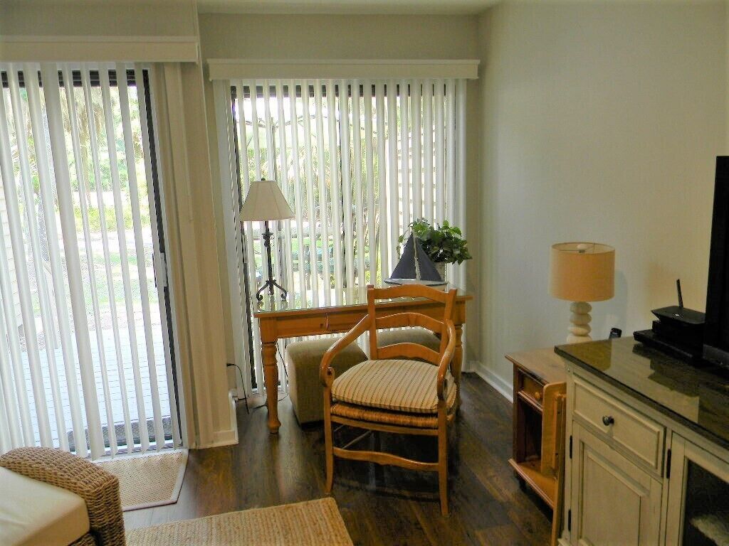 A room with a wooden chair, a desk, a lamp, and a television.
