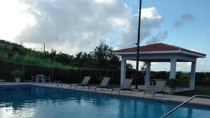 A swimming pool with lounge chairs and a gazebo.