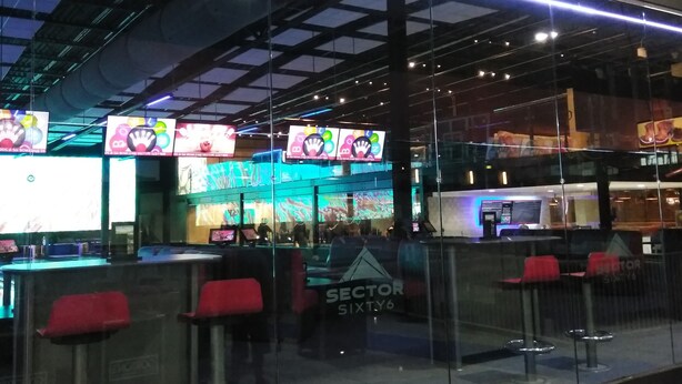 A bowling alley with a neon sign, seating areas, and a counter.