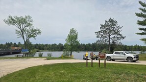 A gravel path leading to a dock by a lake, with a white pickup truck parked nearby. - A Perfect Northern Get-Away On The Scenic Big Creek In Luzerne (Luzerne)