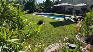 Une piscine entourée d’une pelouse bien entretenue, de mobilier d’extérieur et d’un bâtiment en pierre.