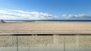 Ein Strand mit blauem Himmel und einem Rettungsturm in der Ferne.