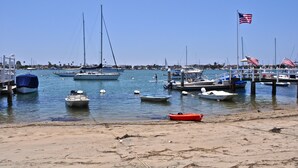 Ein Yachthafen mit verschiedenen vertäuten Booten, ein Sandstrand und ein klarer, blauer Himmel.