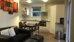 A compact living space with a dining area, kitchenette, and a sofa with a cushion. - Angie's Rural Retreat (Lower Hutt)